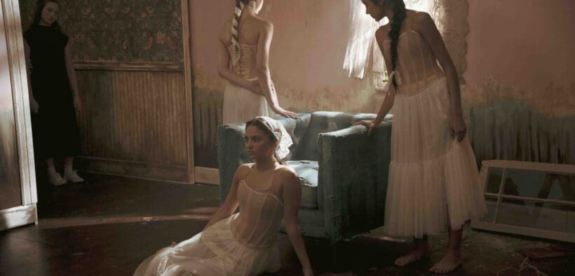 Dancers in soft, neutral costumes pose inside a vintage-style room with textured walls and dramatic lighting in a scene from the Arizona-made cine-dance film Rooms, screening February 24 in Tucson.