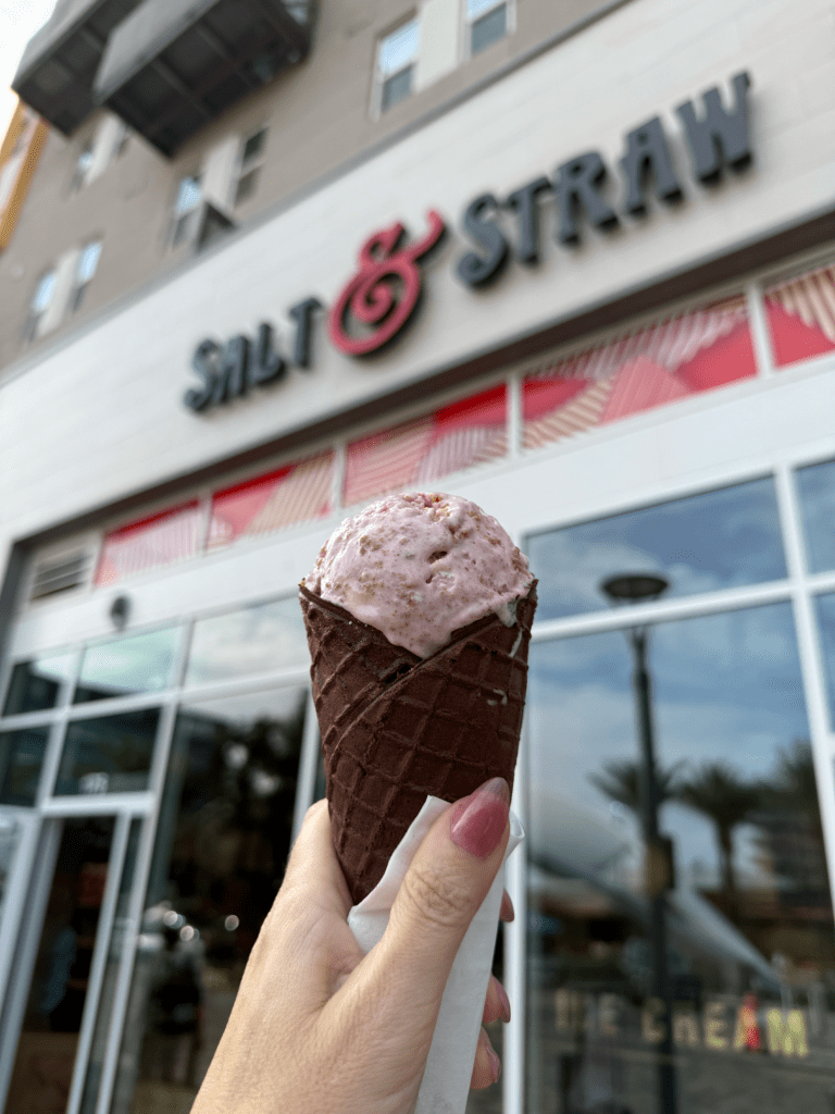 Hand holding an ice cream cone in front of the Salt & Straw storefront at Novus Place in Tempe.