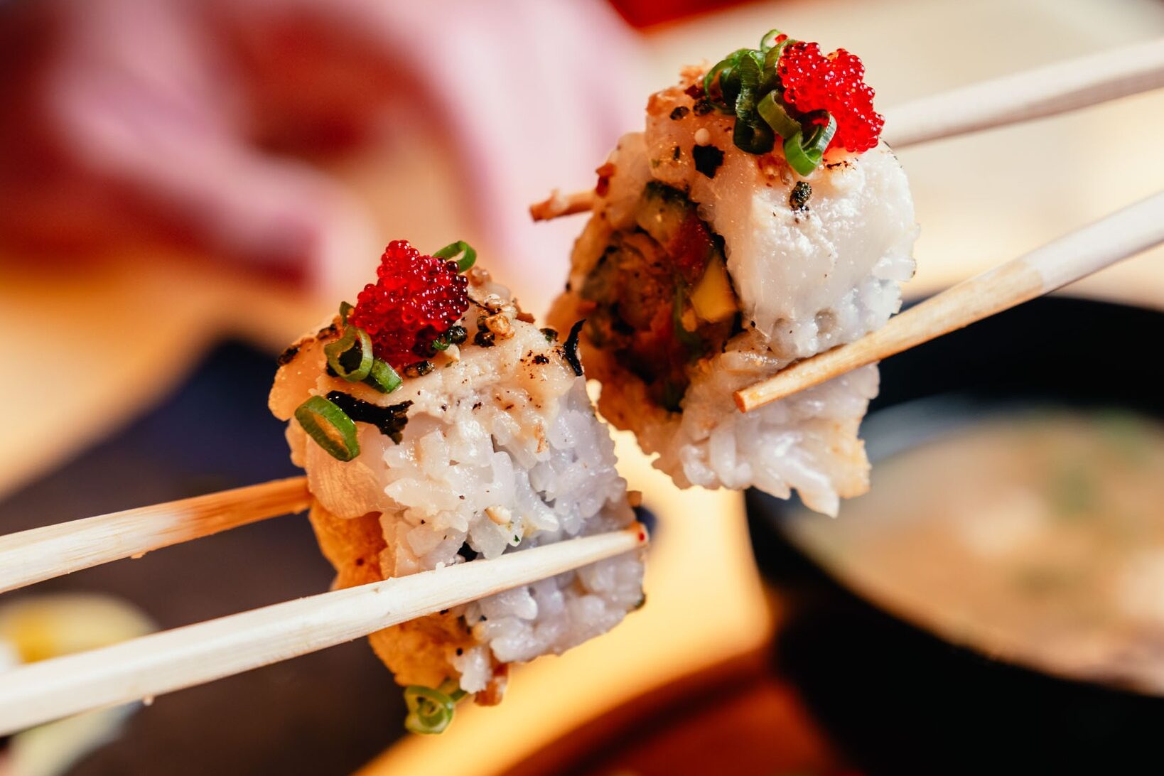 A close-up of sushi rolls topped with roe and scallions held with chopsticks, part of a Valentine’s Day dining experience at Silverton Casino Lodge in Las Vegas.