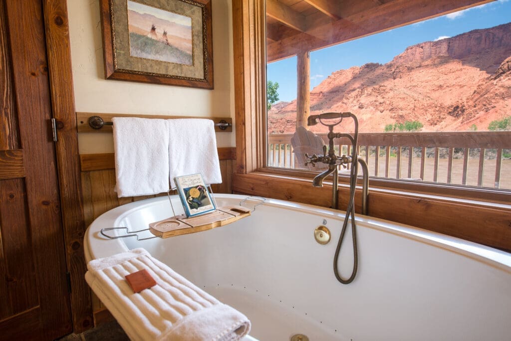Soaking tub with balcony views of red rock cliffs inside a Sorrel River Ranch suite in Moab, Utah.