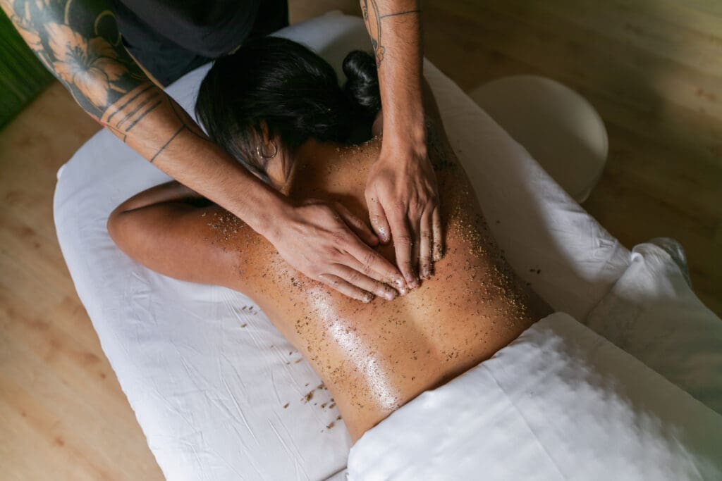 A spa therapist performs a body scrub treatment on a guest lying face down on a massage table at Spa Brezza in San Diego, California.