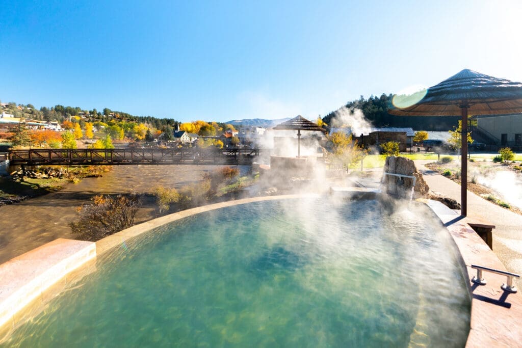 Geothermal soaking pool at The Springs Resort in Pagosa Springs overlooking the San Juan River with mountain views and rising steam. 