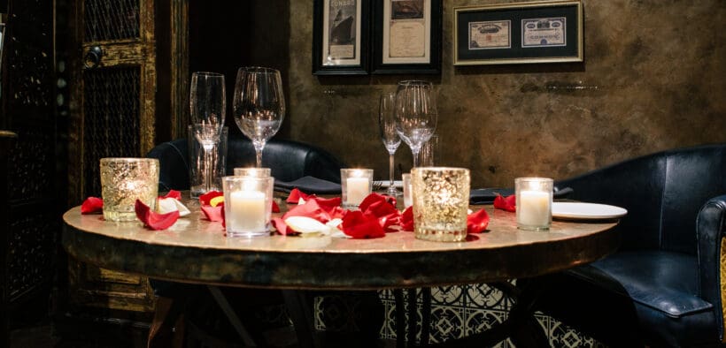 Romantic Valentine’s Day dinner setting with candles and rose petals at T. Cook's restaurant at Royal Palms Resort and Spa.