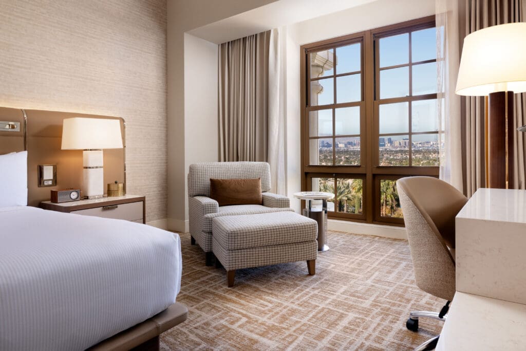 Grand Suite bedroom at Green Valley Ranch with upholstered chair, large window view and contemporary furnishings.