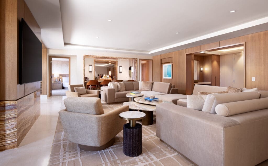 Spacious Strip Suite living room at Green Valley Ranch with large sectional sofa, lounge chairs and marble coffee tables.