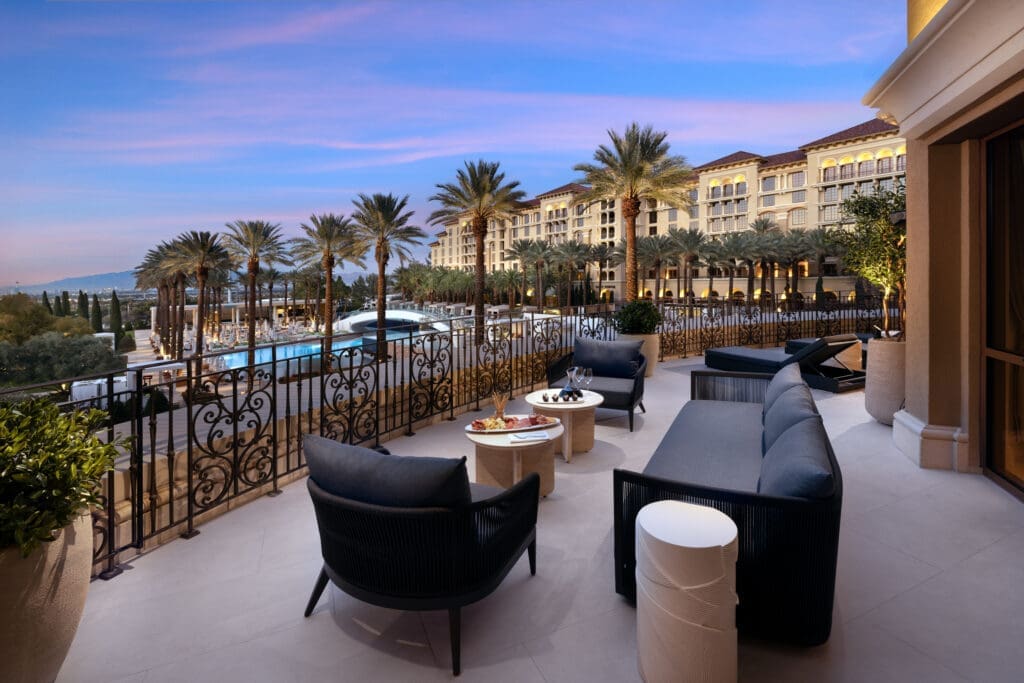 Outdoor patio of the Strip Suite at Green Valley Ranch overlooking the resort pool area and palm-lined grounds at sunset.