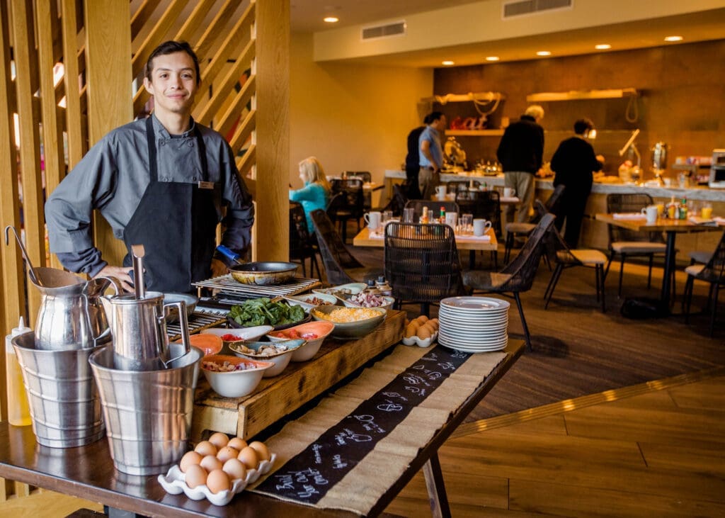 Chef preparing made-to-order omelets at a brunch station with fresh ingredients and eggs displayed on a counter.