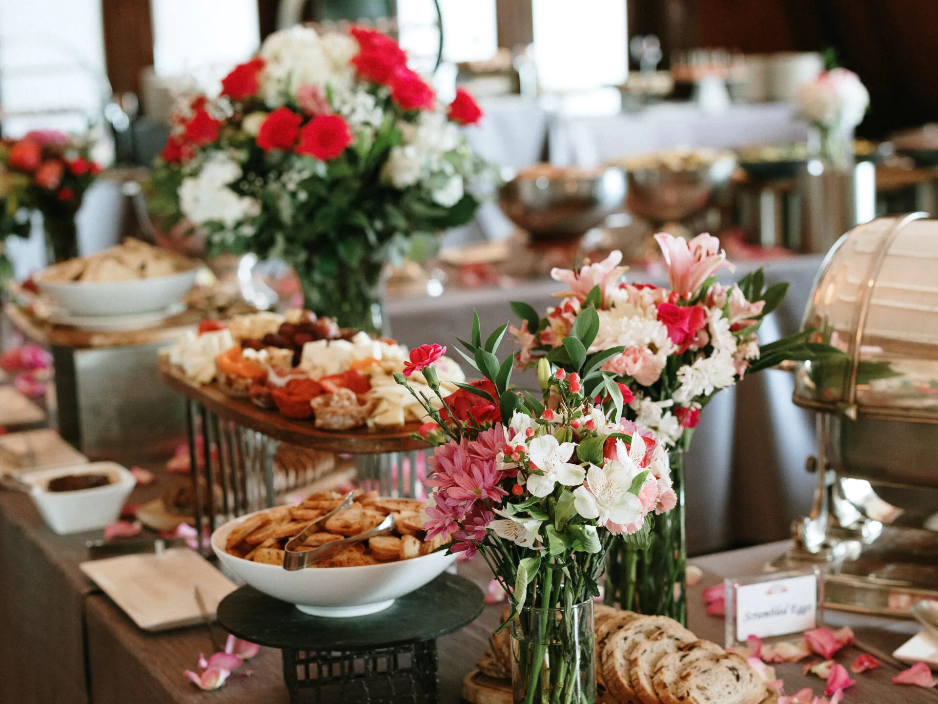 Elegant brunch buffet with fresh flowers, pastries and assorted dishes displayed on a beautifully decorated table in a refined dining space.