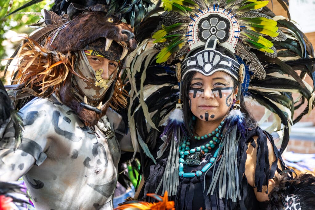 Two cultural performers wearing elaborate feathered headdresses, ceremonial face paint and traditional attire pose during the Spirits of Mexico Festival at Heritage Square in Phoenix.