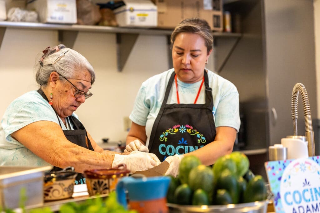 Two women prepare food during a live cooking demonstration featuring traditional Sonoran cuisine at the Spirits of Mexico Festival.