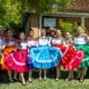 A group of folklórico dancers wearing brightly colored dresses and traditional attire pose together in front of a historic building at Heritage Square in Phoenix.