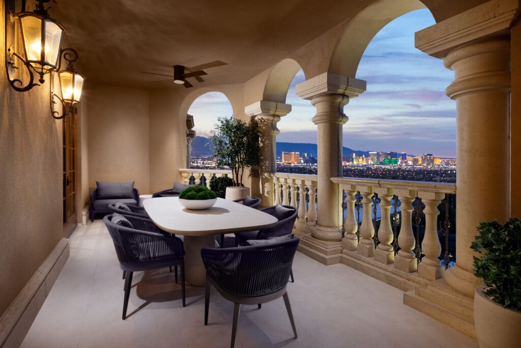 Outdoor terrace at Green Valley Ranch with dining table, arched columns and views of the Las Vegas Strip at dusk.
