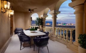 Outdoor terrace at Green Valley Ranch with dining table, arched columns and views of the Las Vegas Strip at dusk.