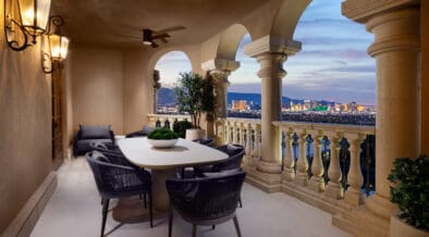 Outdoor terrace at Green Valley Ranch with dining table, arched columns and views of the Las Vegas Strip at dusk.