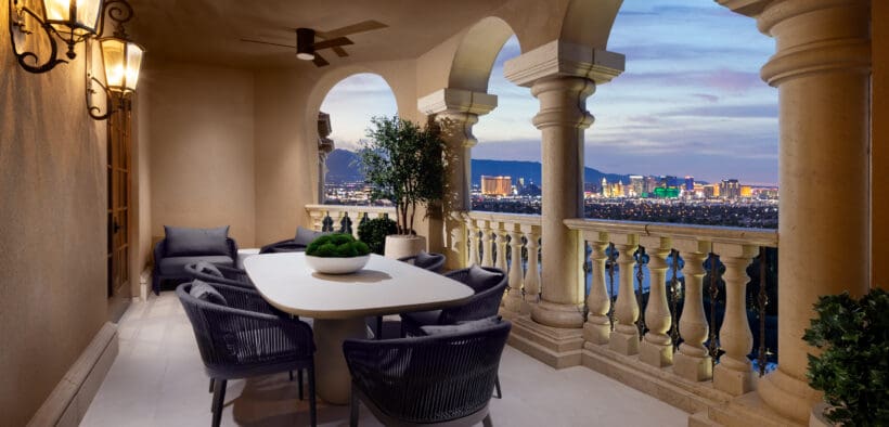 Outdoor terrace at Green Valley Ranch with dining table, arched columns and views of the Las Vegas Strip at dusk.