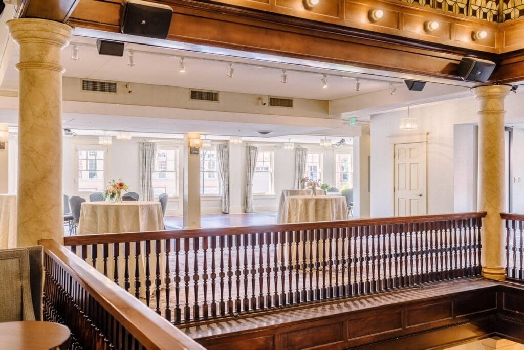 Interior of a historic hotel mezzanine at Hotel Boulderado with round tables, white tablecloths and large windows set for an Easter brunch.