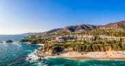 Aerial view of Laguna Beach coastline with turquoise water, sandy beach and hillside homes.