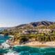 Aerial view of Laguna Beach coastline with turquoise water, sandy beach and hillside homes.
