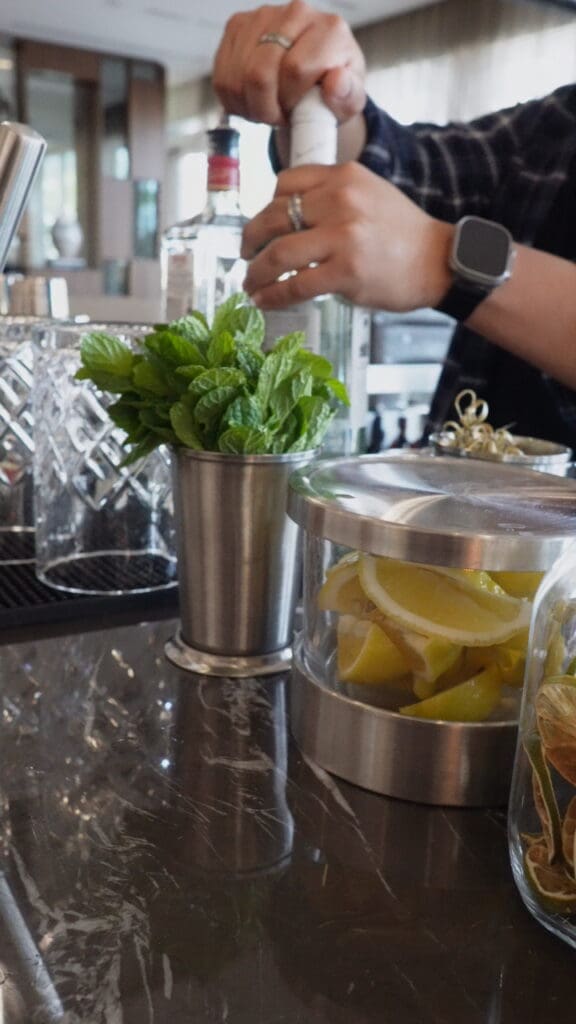 Bartender preparing a cocktail with fresh mint and citrus at the AC Hotel Scottsdale Old Town bar.