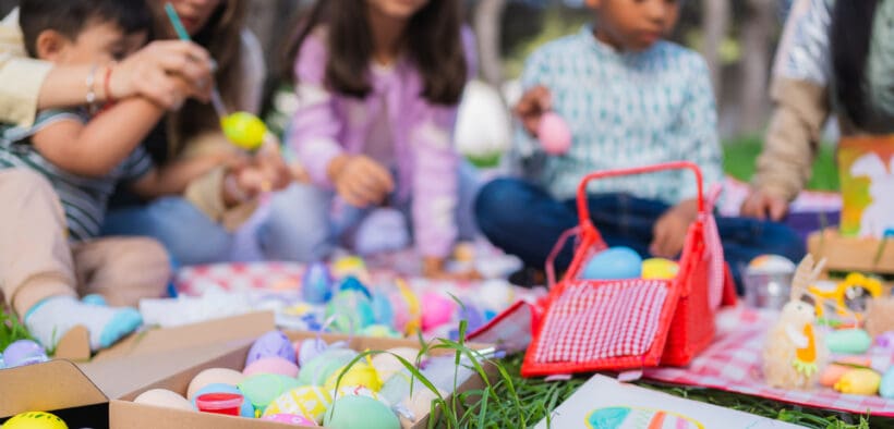 Family and friends are painting colorful easter eggs during an outdoor celebration in New Mexico.
