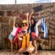 Group of friends posing for a photo in front of a rustic wooden sign display on South Padre Island.