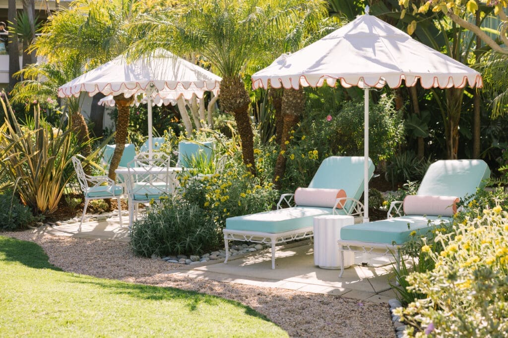 Pavilion Hotel courtyard with pastel lounge chairs, umbrellas and lush landscaping on Catalina Island showcasing Avalon hotel outdoor space and coastal design.