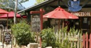 Colorful coffee shop patio with red umbrellas and rustic signage in Madrid, New Mexico.
