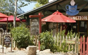 Colorful coffee shop patio with red umbrellas and rustic signage in Madrid, New Mexico.