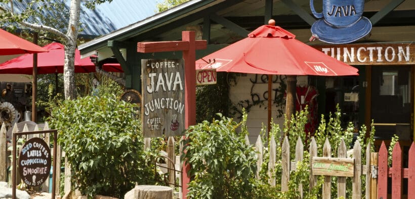 Colorful coffee shop patio with red umbrellas and rustic signage in Madrid, New Mexico.