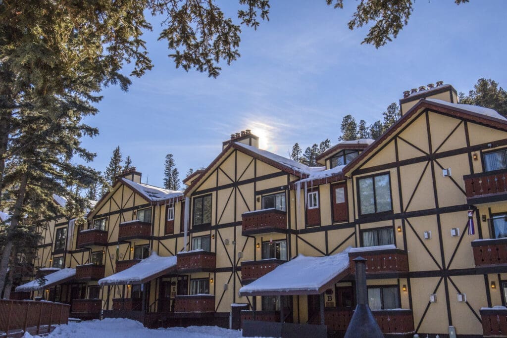 Snow-covered alpine-style lodge surrounded by pine trees in Red River, New Mexico.