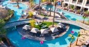 Aerial view of JW Marriott Phoenix Desert Ridge’s AquaRidge WaterPark featuring a winding lazy river, palm trees, cabanas and bright pool floats in Phoenix, Arizona.