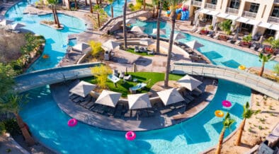 Aerial view of JW Marriott Phoenix Desert Ridge’s AquaRidge WaterPark featuring a winding lazy river, palm trees, cabanas and bright pool floats in Phoenix, Arizona.