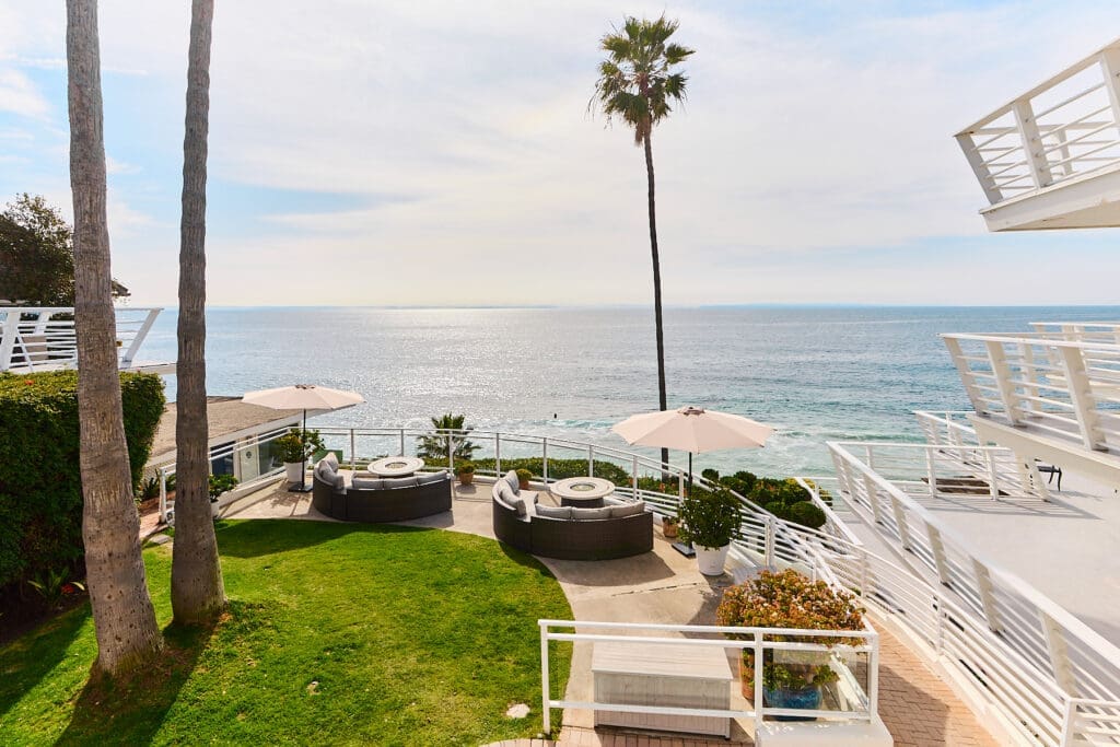 Oceanfront hotel terrace with lounge seating and palm trees overlooking the Pacific Ocean in Laguna Beach.