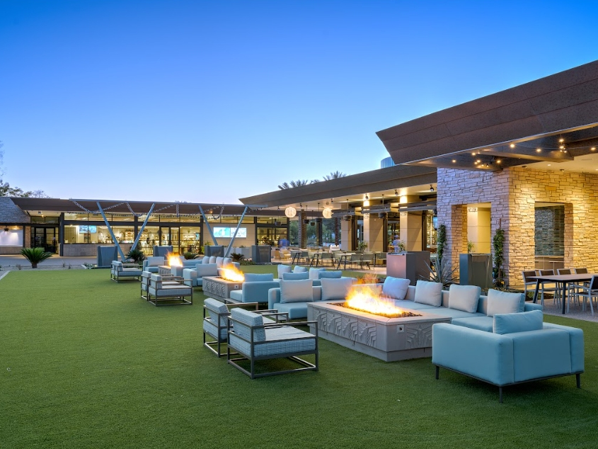 Outdoor patio at Adobe Bar & Grille at Arizona Biltmore Golf Club with lounge seating, fire pits and views of the golf course at sunset.
