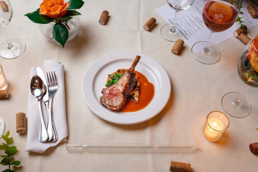 Elegant plated lamb entrée served with wine on a candlelit table at a Denver vineyard restaurant.