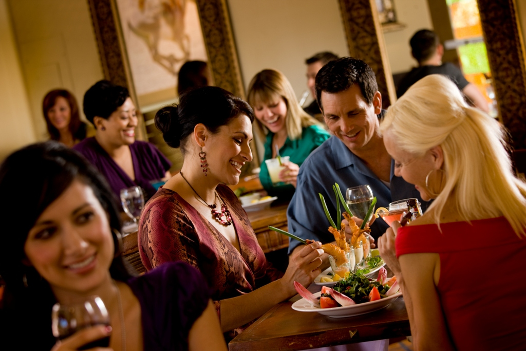 Group of people enjoying a Mother’s Day brunch at a resort restaurant, sharing seafood dishes and drinks in a warm, lively dining setting in Arizona.