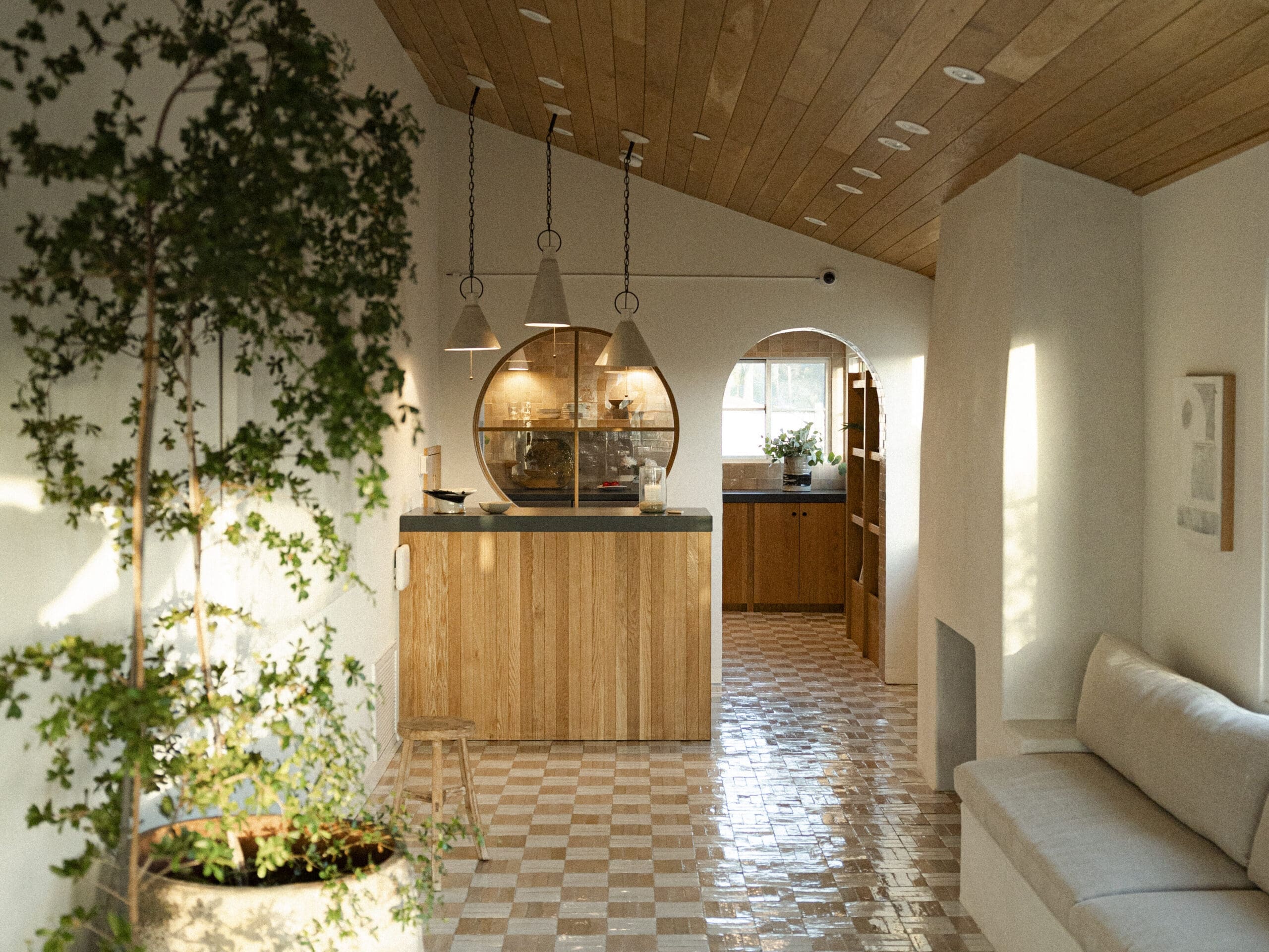 Lobby interior at Woods Cove Inn with checkered tile floor, wood ceiling, plants and arched doorway.