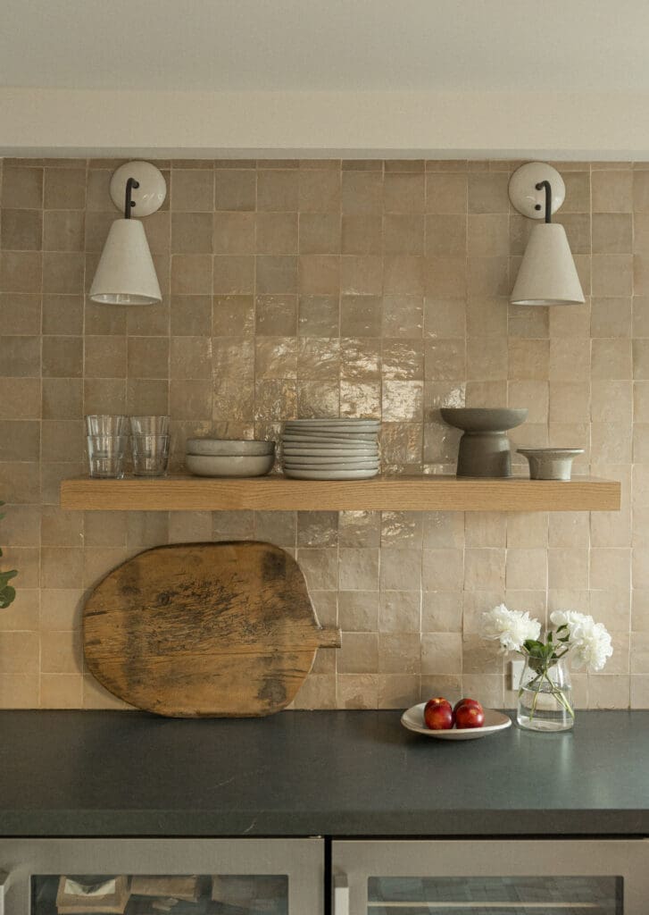 Styled kitchen shelf with ceramics, wood board and neutral tile backsplash at Woods Cove Inn.