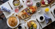 A spread of brunch foods: pancakes eggs, coffee, charcuterie boards on a talbe at Greenfinch, Estancia La Jolla Hotel & Spa.