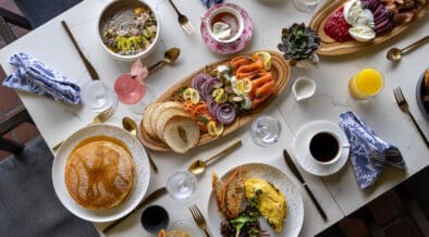 A spread of brunch foods: pancakes eggs, coffee, charcuterie boards on a talbe at Greenfinch, Estancia La Jolla Hotel & Spa.