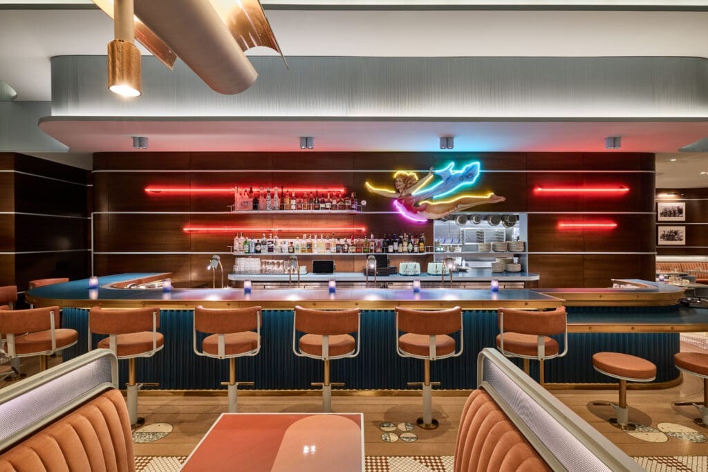 Interior of F/Sixteen at The REMI Scottsdale featuring a retro-inspired bar, neon signage, colorful seating and a stylish, modern restaurant design in Scottsdale Arizona.
