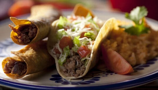 Flautas and ground beef tacos served with rice and garnish at El Paso Mexican restaurant.