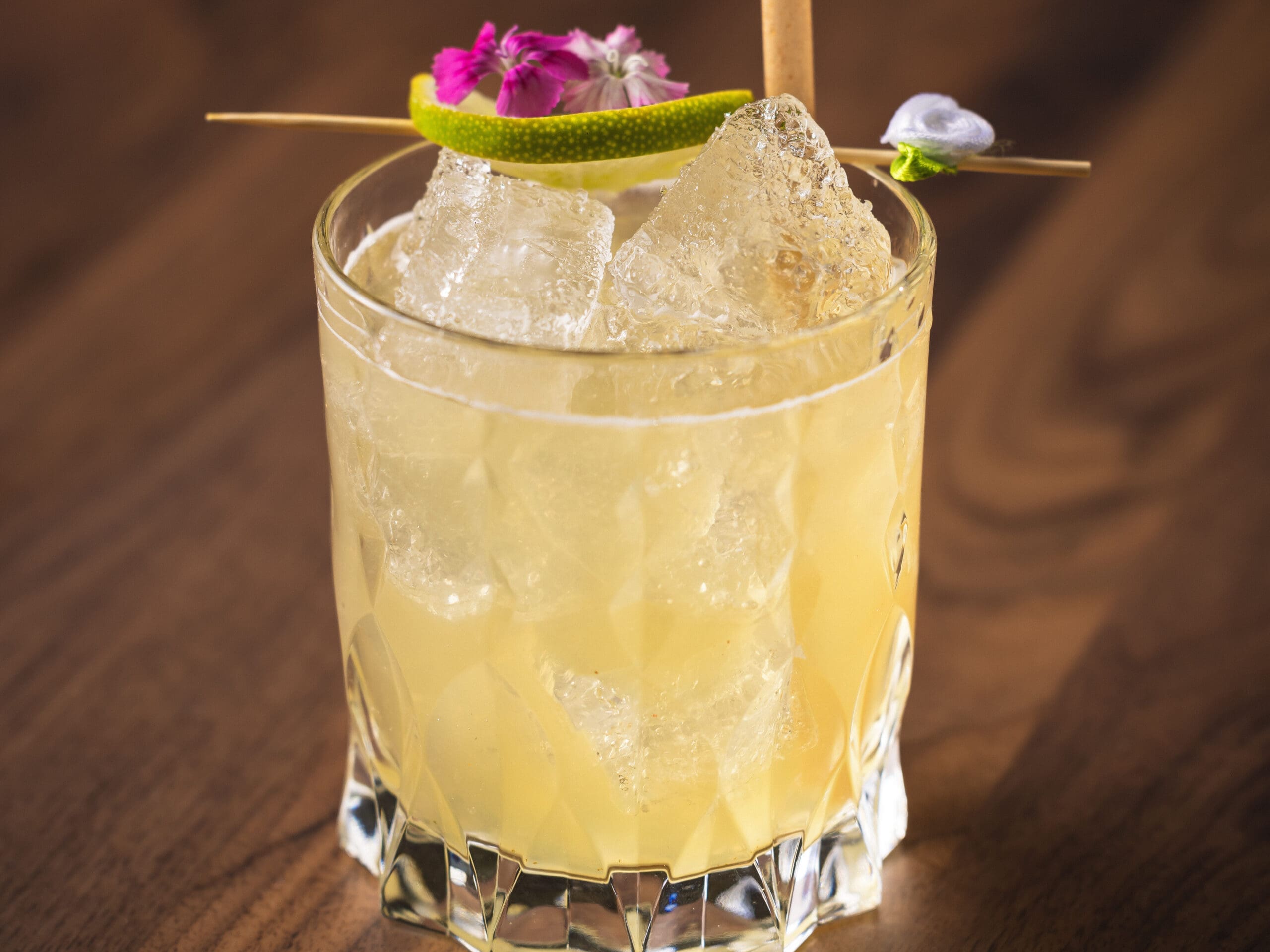 Craft cocktail with lime garnish and edible flowers at The Guest House Scottsdale.