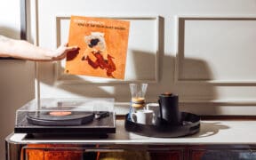 Hand holding Robert Johnson vinyl record near record player in hotel room with coffee setup at Gunter Hotel San Antonio.