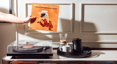 Hand holding Robert Johnson vinyl record near record player in hotel room with coffee setup at Gunter Hotel San Antonio.