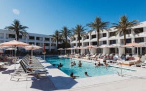Outdoor pool scene at Hotel Solaya Scottsdale with cabanas lounge chairs and guests swimming.