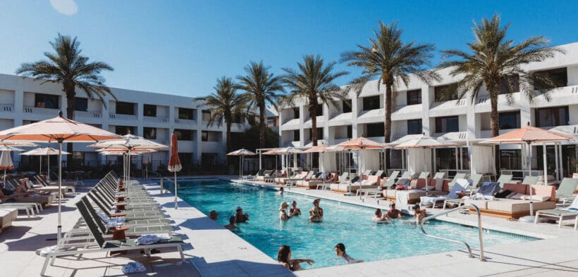 Outdoor pool scene at Hotel Solaya Scottsdale with cabanas lounge chairs and guests swimming.