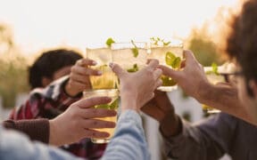 LombardoHappy multiethnic friends having fun cheering with Kentucky Derby cocktails outdoors.