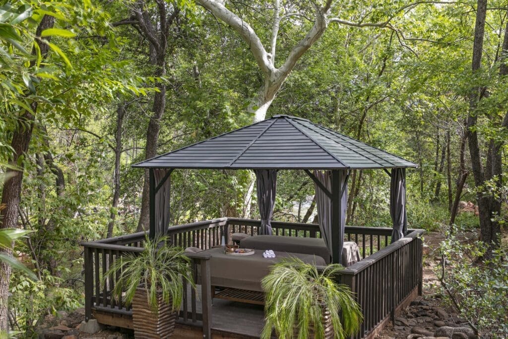 Outdoor massage cabana surrounded by trees at L’Auberge de Sedona creekside spa in Sedona Arizona.