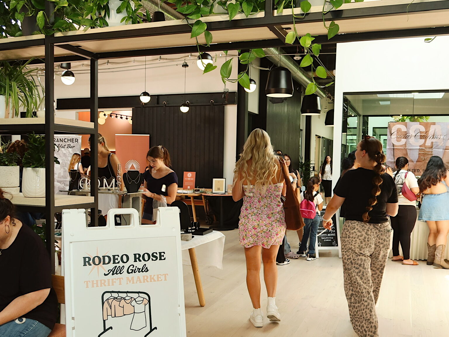 Indoor Rodeo Rose Market scene with shoppers walking past vendor booths and event signage in Scottsdale Arizona.